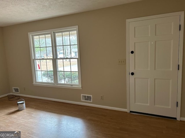 empty room featuring a textured ceiling, a healthy amount of sunlight, and light wood-type flooring