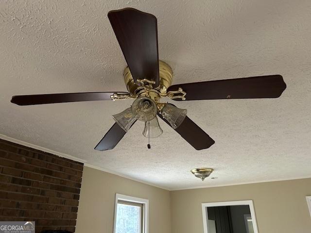 room details featuring ceiling fan, ornamental molding, and a textured ceiling