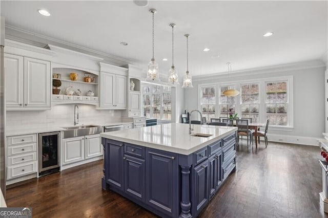 kitchen with wine cooler, blue cabinets, sink, and white cabinets