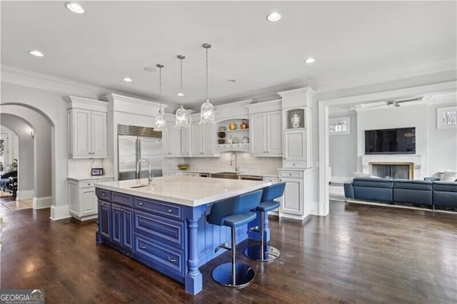 kitchen featuring built in refrigerator, an island with sink, blue cabinets, and white cabinets