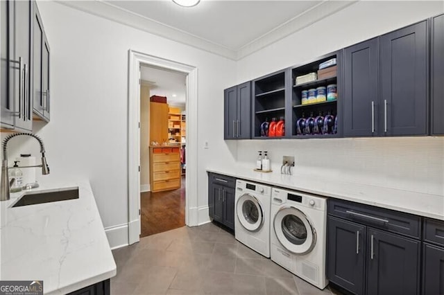 washroom with sink, dark tile patterned floors, washing machine and dryer, cabinets, and ornamental molding