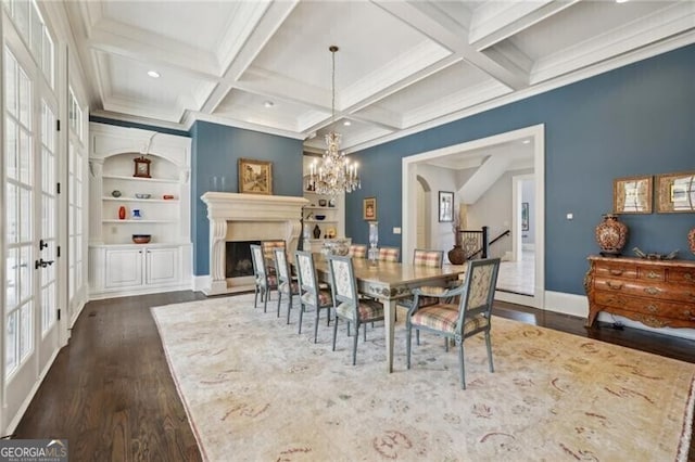 dining room with an inviting chandelier, coffered ceiling, dark hardwood / wood-style flooring, built in shelves, and beamed ceiling