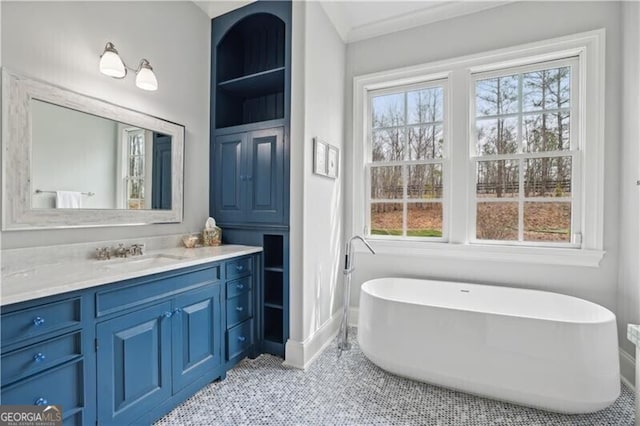 bathroom with crown molding, a healthy amount of sunlight, vanity, and a tub