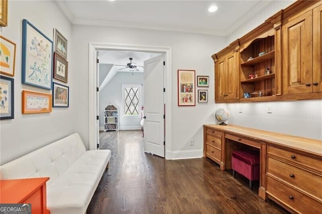 office space with dark hardwood / wood-style flooring, crown molding, built in desk, and ceiling fan