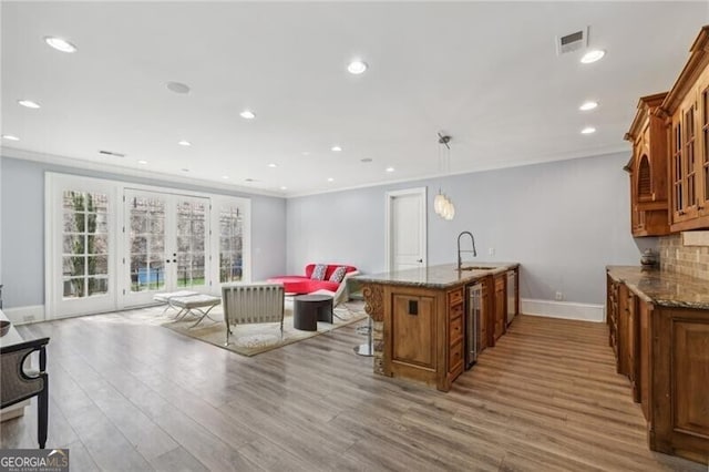 kitchen with stone counters, decorative light fixtures, sink, a kitchen bar, and french doors