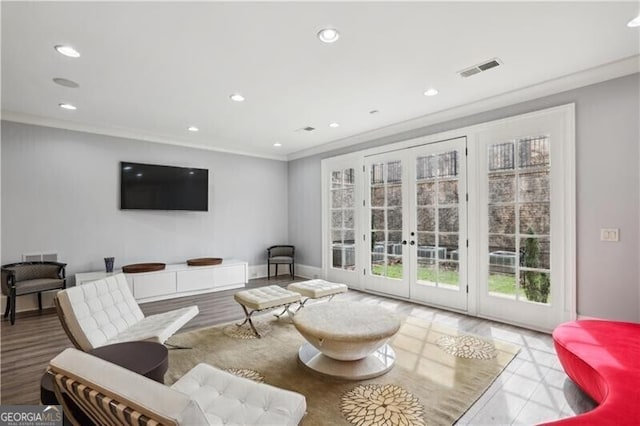 living room with light hardwood / wood-style floors, ornamental molding, and french doors