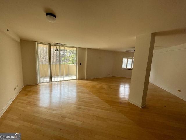 empty room with expansive windows and light wood-type flooring