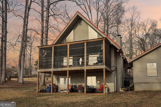 back house at dusk with cooling unit and a sunroom