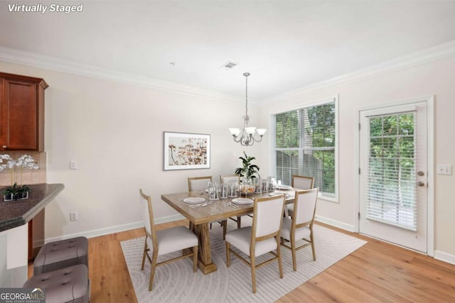 dining space with ornamental molding, a chandelier, and light hardwood / wood-style flooring