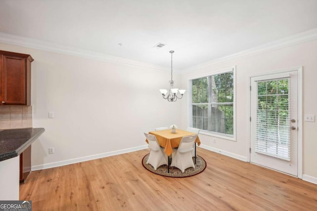 dining area with crown molding, a chandelier, and light hardwood / wood-style flooring