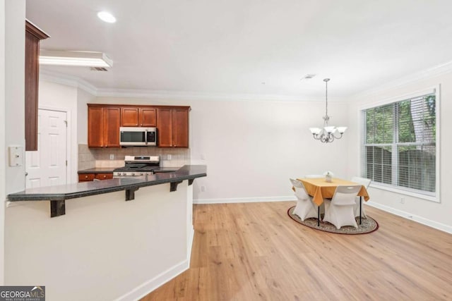 kitchen with hanging light fixtures, decorative backsplash, a breakfast bar area, and appliances with stainless steel finishes