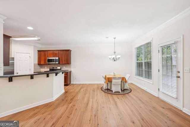 kitchen featuring appliances with stainless steel finishes, a kitchen breakfast bar, light hardwood / wood-style floors, decorative backsplash, and decorative light fixtures