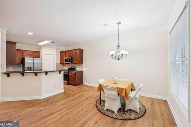 dining space with crown molding, a chandelier, and light hardwood / wood-style flooring