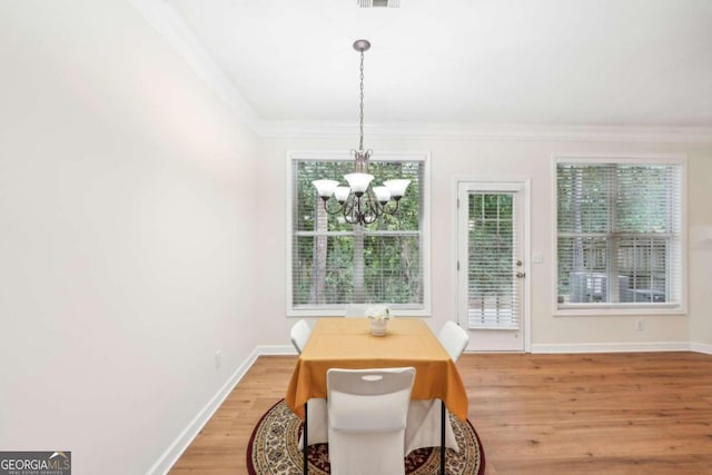 dining room with an inviting chandelier, hardwood / wood-style flooring, and crown molding