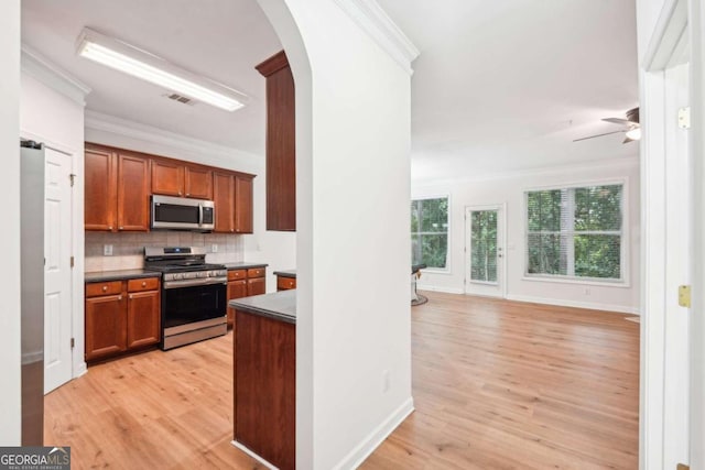 kitchen with tasteful backsplash, ornamental molding, and appliances with stainless steel finishes