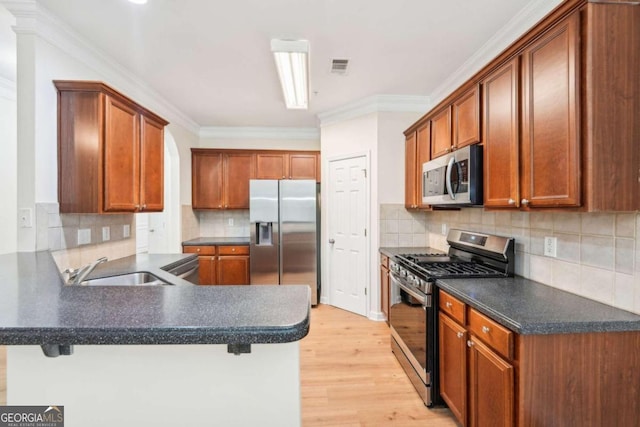 kitchen with sink, a kitchen breakfast bar, kitchen peninsula, and appliances with stainless steel finishes