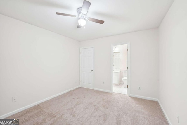 unfurnished bedroom featuring light carpet, connected bathroom, and ceiling fan