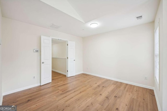 unfurnished room with vaulted ceiling and light hardwood / wood-style floors