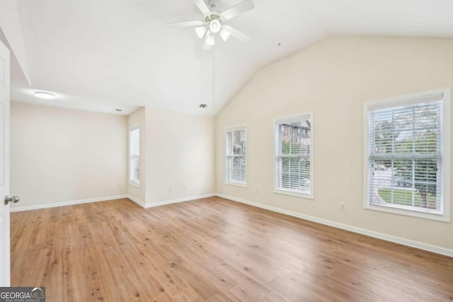 spare room with lofted ceiling, a wealth of natural light, ceiling fan, and light wood-type flooring