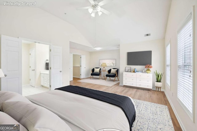 bedroom featuring connected bathroom, high vaulted ceiling, and light hardwood / wood-style flooring