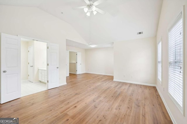 unfurnished bedroom featuring connected bathroom, light hardwood / wood-style flooring, and high vaulted ceiling