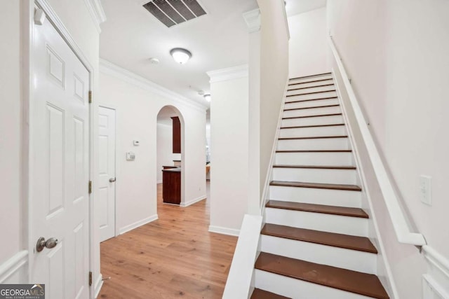 stairway featuring ornamental molding and wood-type flooring