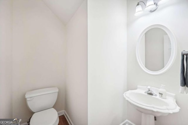 bathroom with lofted ceiling, sink, and toilet