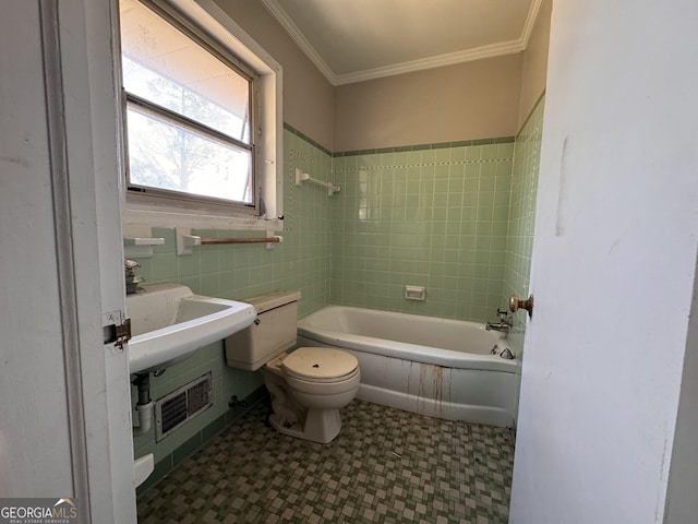 bathroom with tile walls, crown molding, tiled shower / bath combo, and toilet