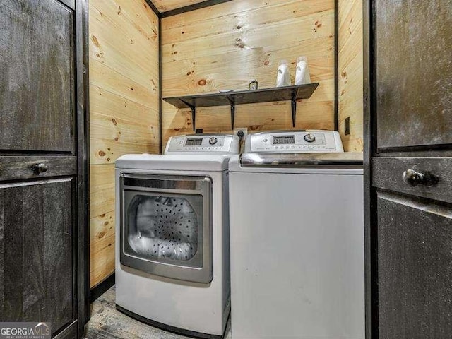 laundry room featuring separate washer and dryer and wood walls