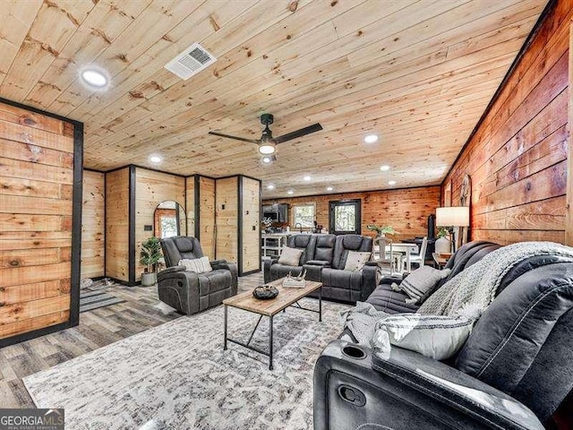 living room featuring hardwood / wood-style flooring, ceiling fan, wooden walls, and wood ceiling