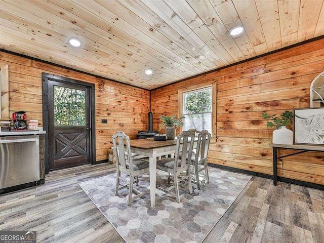 dining room featuring wood ceiling, a healthy amount of sunlight, wooden walls, and hardwood / wood-style flooring