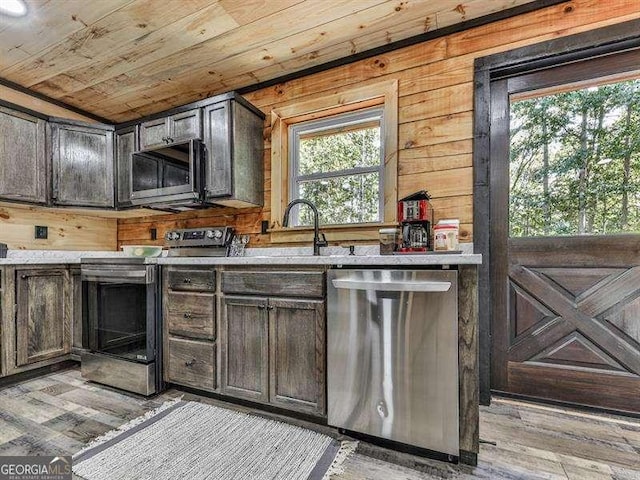 kitchen with appliances with stainless steel finishes, wooden walls, dark brown cabinetry, light hardwood / wood-style floors, and wooden ceiling