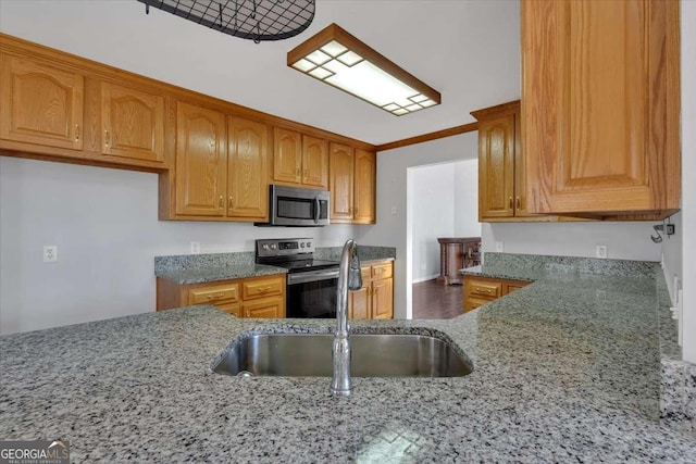 kitchen featuring stainless steel appliances, stone countertops, sink, and ornamental molding