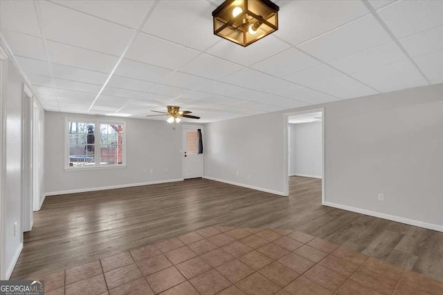 empty room featuring dark hardwood / wood-style floors, a drop ceiling, and ceiling fan