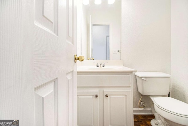 bathroom featuring parquet floors, vanity, and toilet