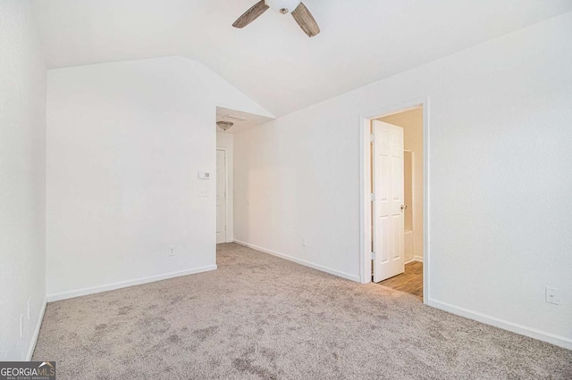 carpeted spare room featuring vaulted ceiling and ceiling fan