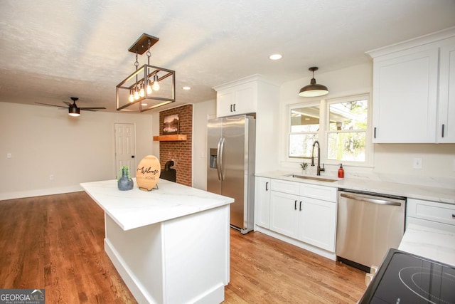 kitchen featuring sink, white cabinetry, stainless steel appliances, a kitchen island, and decorative light fixtures