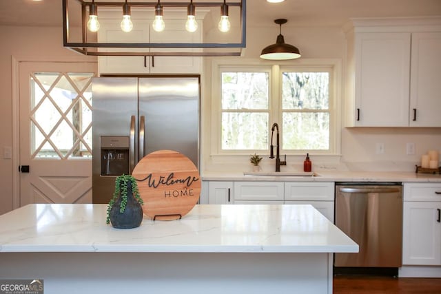 kitchen with light stone counters, appliances with stainless steel finishes, sink, and white cabinets