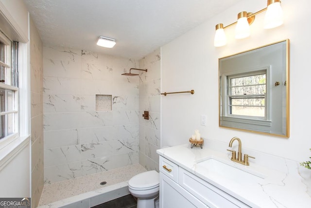 bathroom featuring vanity, a textured ceiling, toilet, and tiled shower