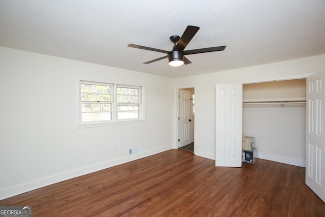 unfurnished bedroom with ceiling fan, a textured ceiling, dark hardwood / wood-style flooring, and a closet