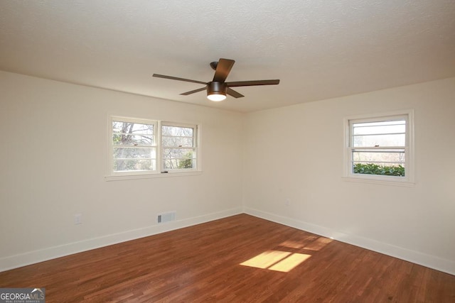 spare room with a wealth of natural light, hardwood / wood-style floors, ceiling fan, and a textured ceiling