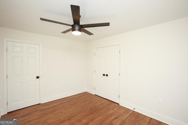 unfurnished bedroom featuring hardwood / wood-style flooring, ceiling fan, and a closet