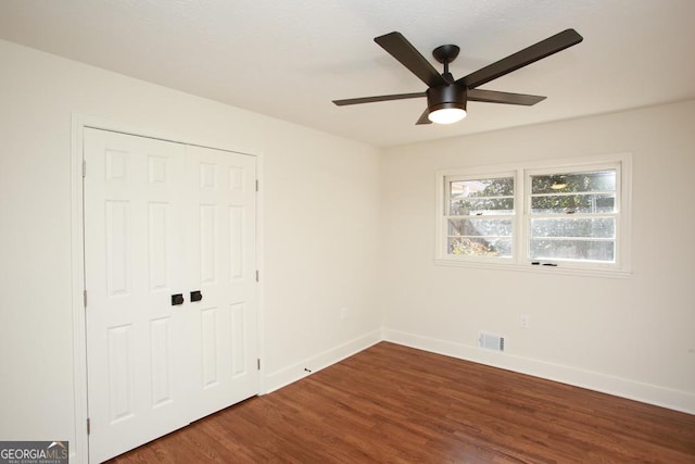 unfurnished bedroom with dark hardwood / wood-style flooring, a closet, and ceiling fan