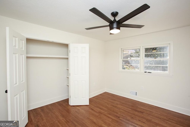 unfurnished bedroom featuring ceiling fan, dark hardwood / wood-style floors, and a closet