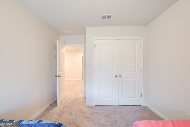 unfurnished bedroom featuring light carpet and a closet