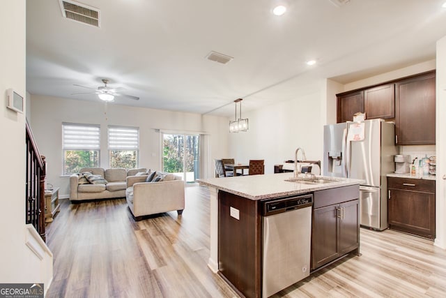 kitchen with decorative light fixtures, sink, a kitchen island with sink, stainless steel appliances, and dark brown cabinets