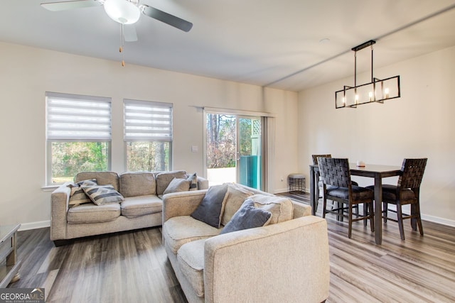 living room featuring hardwood / wood-style flooring, ceiling fan with notable chandelier, and a healthy amount of sunlight