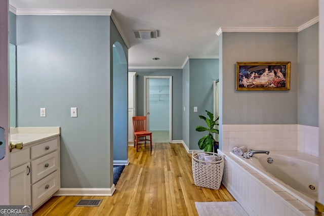 bathroom with vanity, wood-type flooring, ornamental molding, and a tub