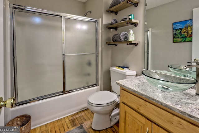 full bathroom with toilet, wood-type flooring, shower / bath combination with glass door, and vanity