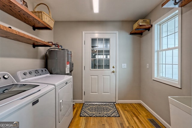 washroom with independent washer and dryer, a wealth of natural light, water heater, and light wood-type flooring